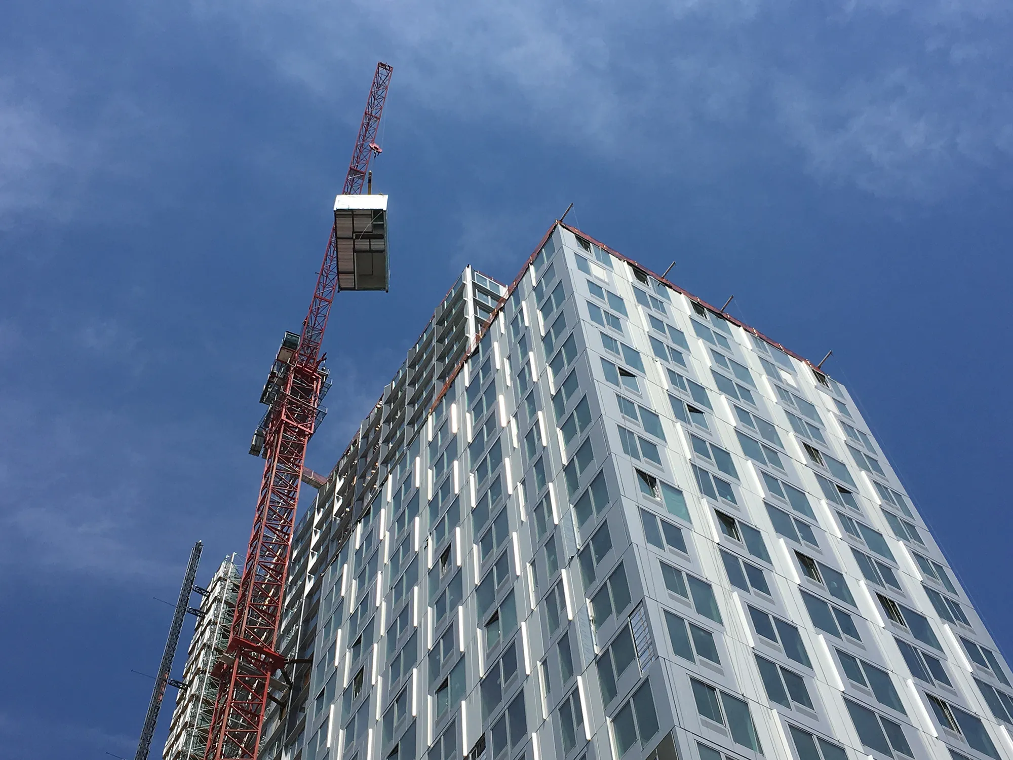 A crane lifting a module onto a high-rise modular tower